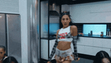 a woman is dancing in a kitchen wearing a crop top that says nike