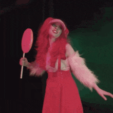 a woman in a pink wig is holding a pink lollipop