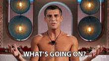a shirtless man with a microphone around his neck is asking what 's going on