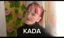 a woman with red hair is standing in front of a curtain with the word kada written on it