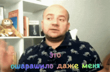 a man wearing a shirt with animals on it says " это " in a foreign language