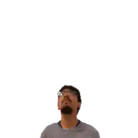 a man wearing glasses looks up at a green cross above his head