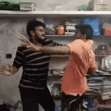 two men are fighting in a room with bookshelves .