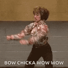 a woman is dancing in a room with the words `` bow chicka wow wow '' .