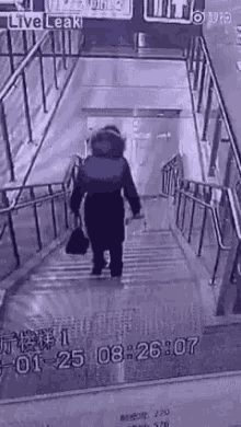 a woman is walking down a set of stairs holding a black bag .