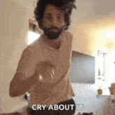 a man with a beard is dancing in a room with the words `` cry about it '' written on his face .