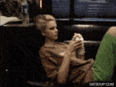 a woman is sitting on a couch eating a sandwich with a gif soup.com watermark in the corner