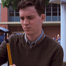 a man in a brown sweater is holding a yellow cane