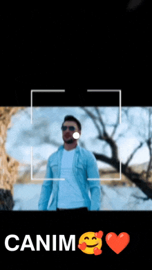 a man in a blue jacket is being photographed by a camera and the words canim are above him