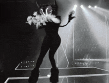 a woman in a devil costume is dancing on a stage with a tumblr logo in the background