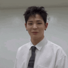 a young man wearing a white shirt and tie is looking at the camera .