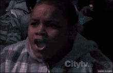 a young boy is sitting in a crowd with his mouth open .
