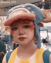 a woman wearing a hat and a yellow shirt has the number 070 on her face