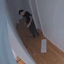 a man in a black shirt is crawling on the floor in a hallway
