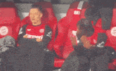 a man wearing a carmeni jersey sits in a stadium seat