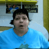a woman in a blue shirt is making a funny face in front of a sign that says web diva luana