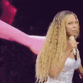 a woman with long blonde hair is holding a microphone .
