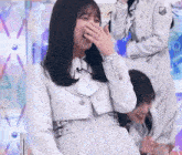a woman is covering her mouth with her hand while another woman laughs .