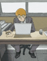 a man is sitting at a desk using a laptop