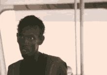 a man is standing in front of a window with the words look at me written on his face .