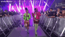 two women are walking down a stage in front of a crowd .