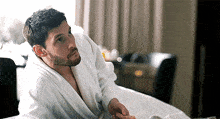 a man in a robe is sitting on a bed