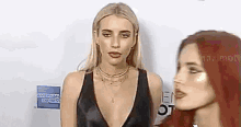 two women standing next to each other on a red carpet .