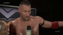 a shirtless wrestler is talking into a microphone with the hashtag #wwe nxt