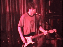 a man singing into a microphone while playing an electric guitar