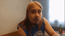 a man with long hair and a beard is wearing a blue shirt that says suomi on it .
