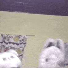 a white stuffed animal is sitting on a table next to a remote control .