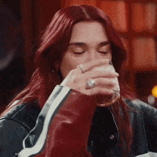 a woman with red hair is drinking a glass of beer in a bar .