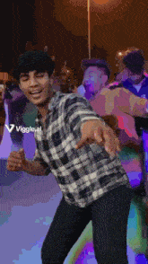 a man in a plaid shirt is dancing in front of a sign that says ' viggle.ai '