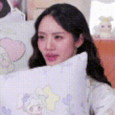 a woman is sitting on a bed holding a pillow in her hand .