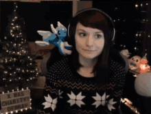 a woman wearing headphones is sitting in front of a christmas tree