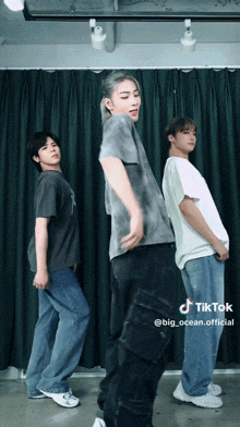 three young men are dancing in front of a green curtain and a tiktok watermark
