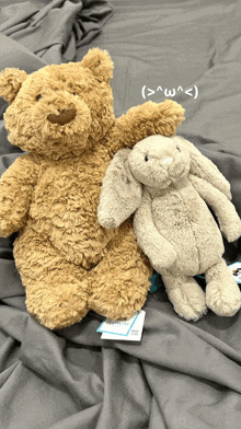 a teddy bear and a stuffed rabbit are laying on a bed