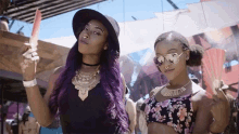 two women with purple hair are standing next to each other and one is holding a watermelon