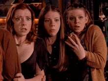 three women are looking at something with a surprised look on their face