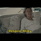 a woman in a hospital bed with the words " respira miley " written above her