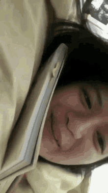 a woman is laying on a bed with a book in her mouth .
