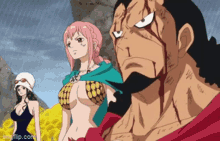 a man with blood on his face is standing next to two women in bikinis .