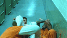 two men in orange jumpsuits are laying on the ground