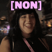 a woman is smiling in front of a sign that says [ non ] on it