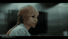 a woman with blonde hair is standing in a dark room and looking at the camera .