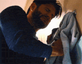 a man with a beard is hanging a towel on a hook on a wall