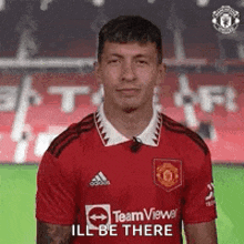 a man in a red soccer jersey is standing on a field .