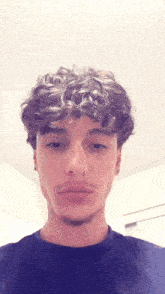 a young man with curly hair and a beard is wearing a black shirt .