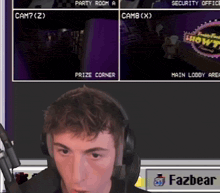 a man wearing headphones sits in front of a screen that says fazbear on it