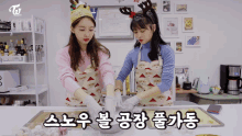 two women wearing aprons and gloves are preparing food in a kitchen with twice tv in the background